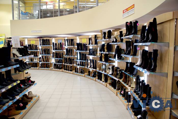 Торговое оборудование для обуви, выставленное по дуге, отделяет торговый зал от подсобки.